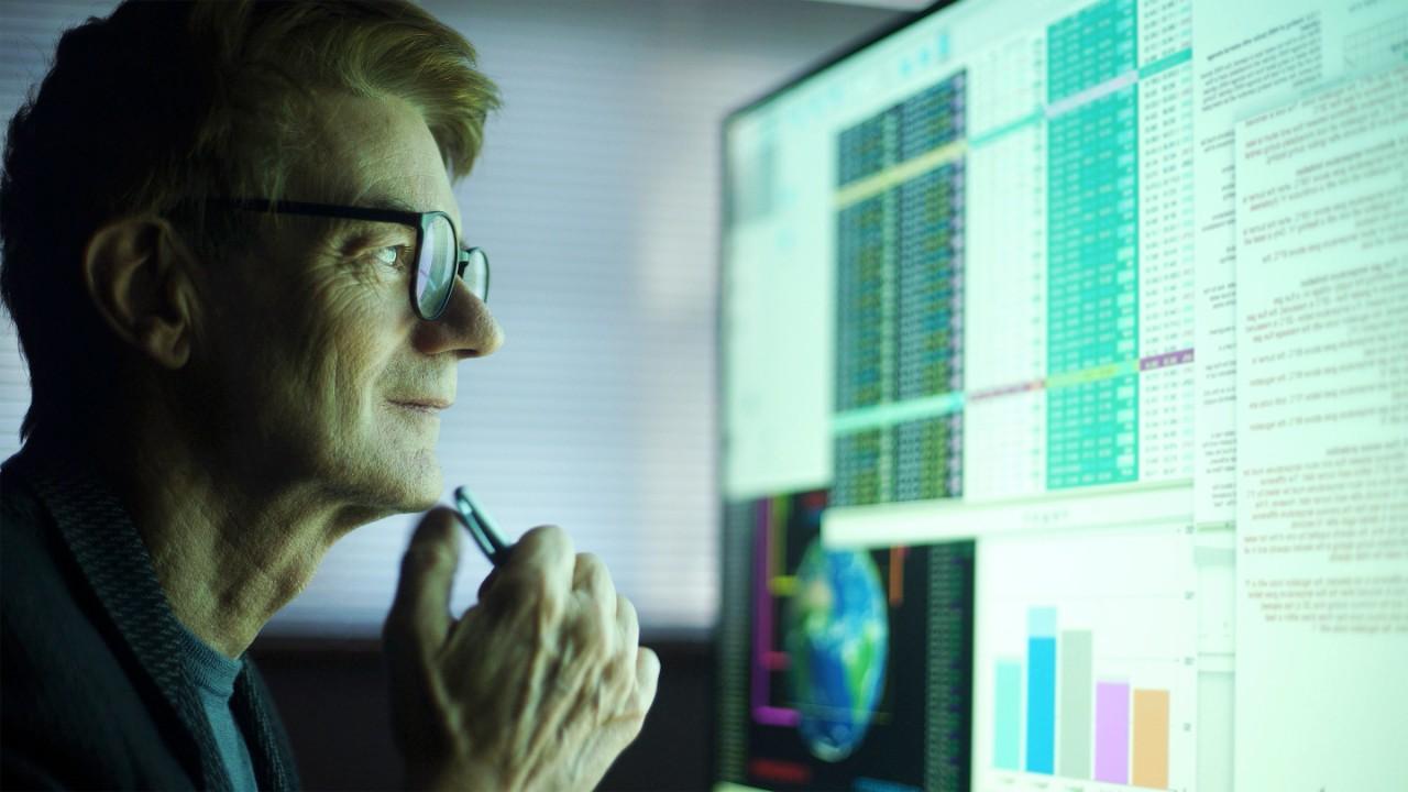 Analyst looks thoughtfully at computer screen