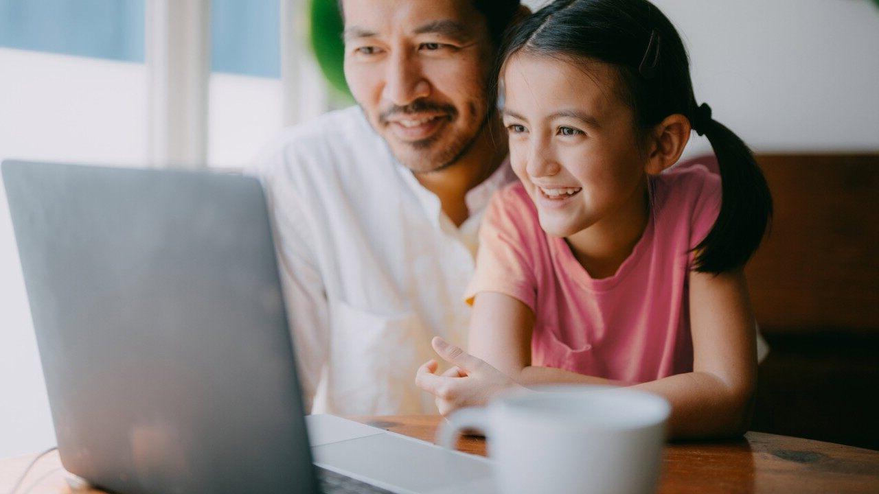 父亲和小女儿在家里用笔记本电脑视频通话